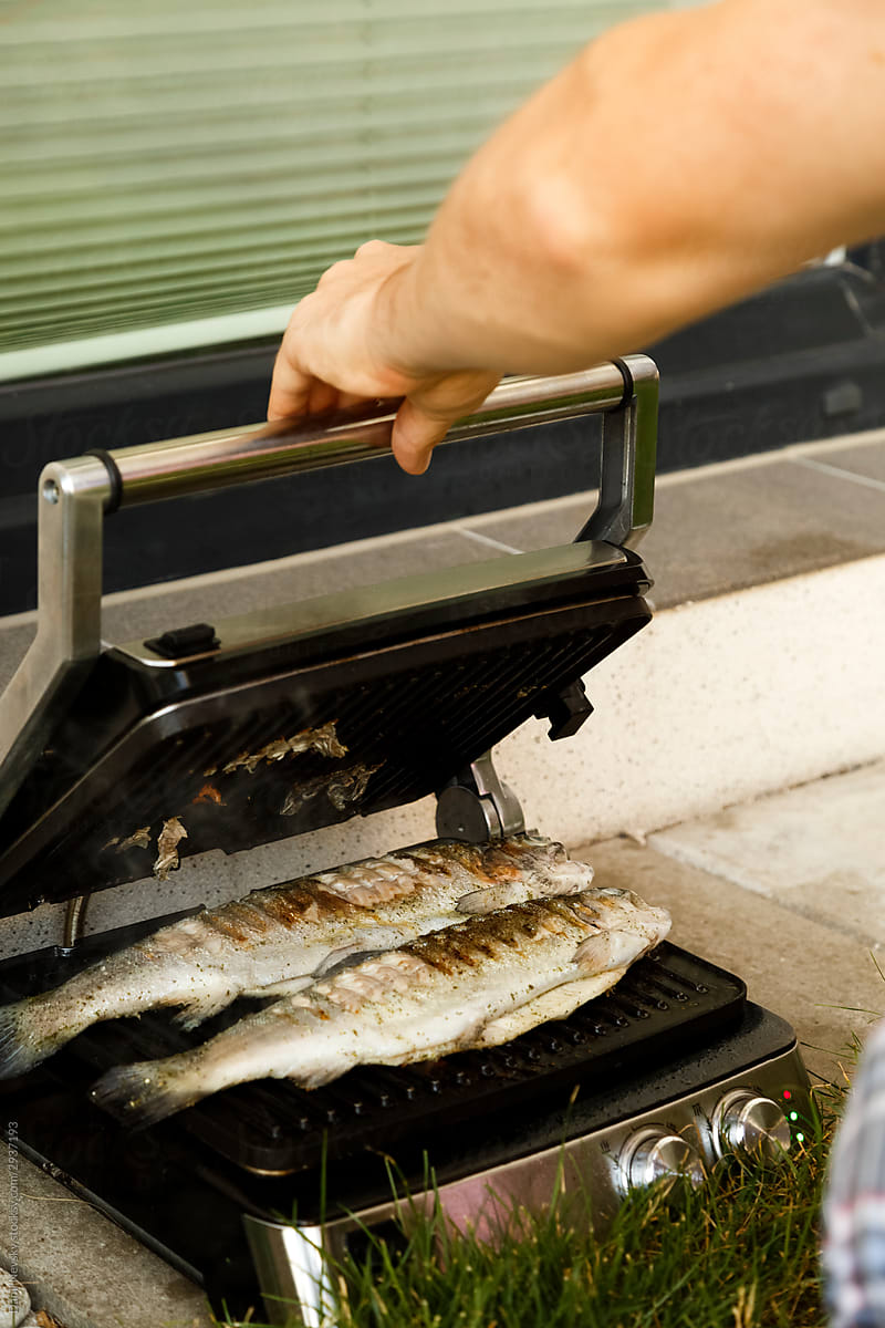 Man cooking fish on grill in yard