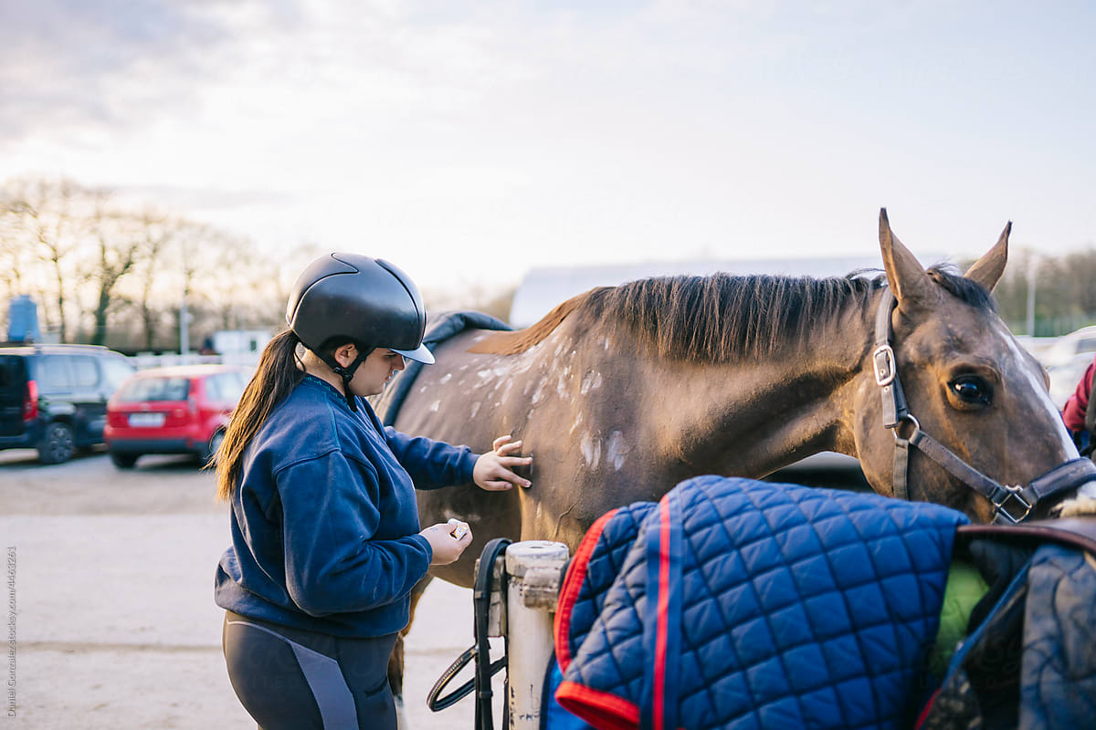 Woman preparing horse for riding in equestrian school