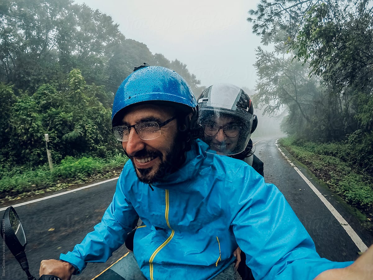 Happy couple on a motorbike traveling on a rainy day