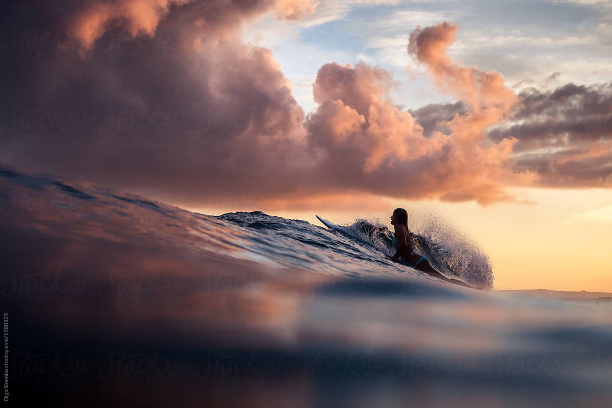 Silhouette Of Woman Surfing In The Ocean At Sunset