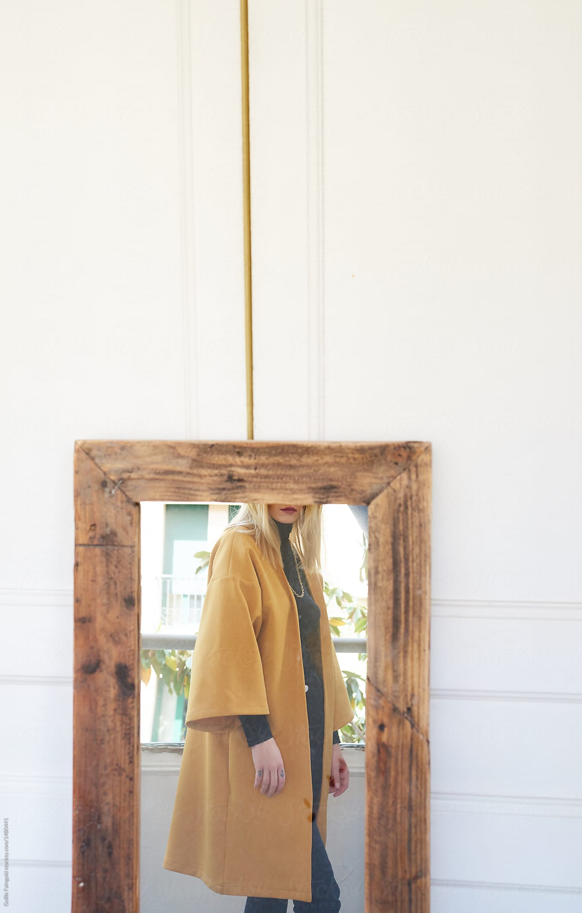 Girl in yellow coat reflecting in mirror