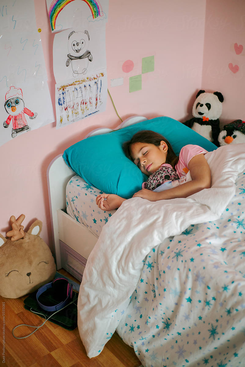A little girl sleeps in a single bed  in her room