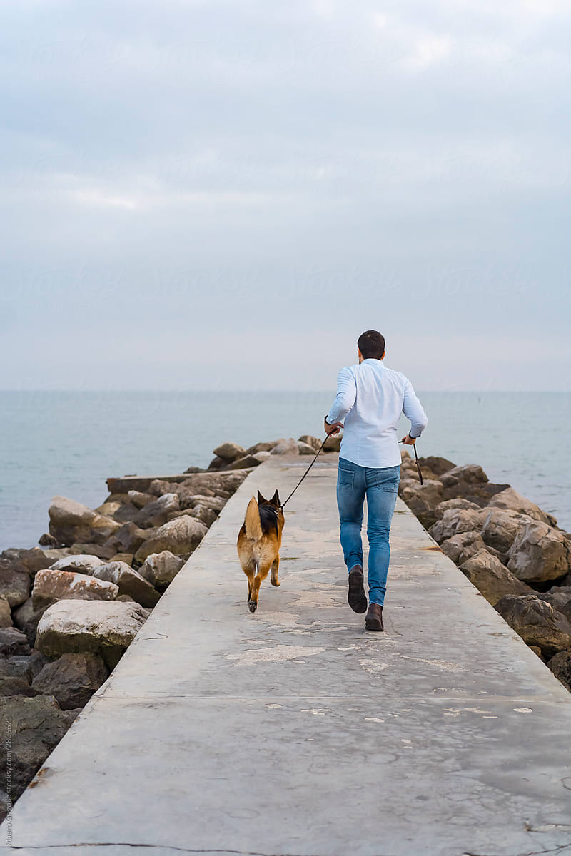 Man walking in a walkway with his dog