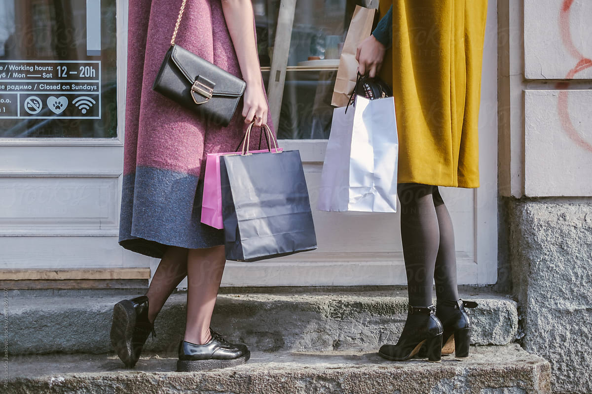 Two Anonymous Women With Shopping Bags Standing In Front Of The Shop