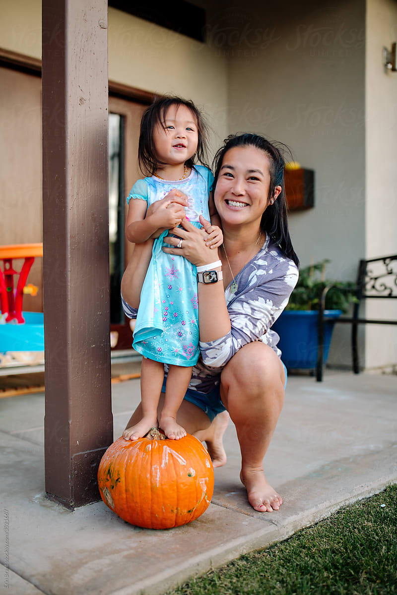 Asian mom with daughter on pumpkin