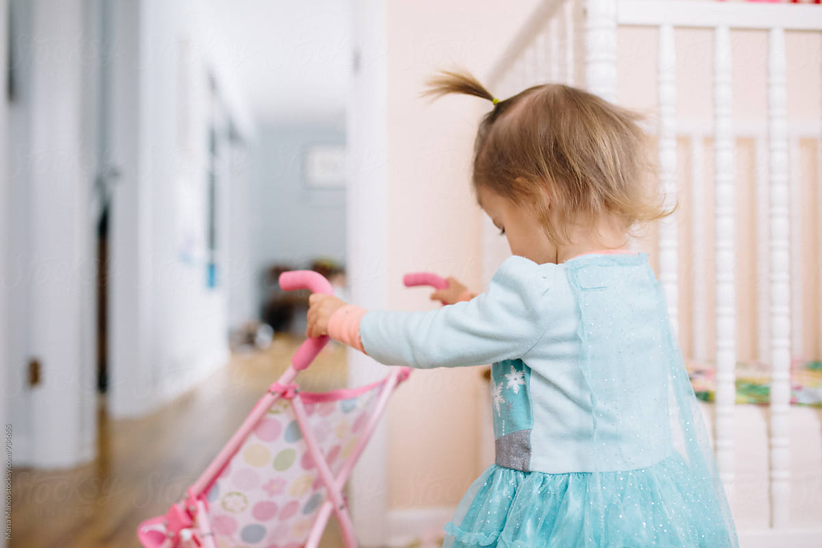 little girl pushes toy stroller inside