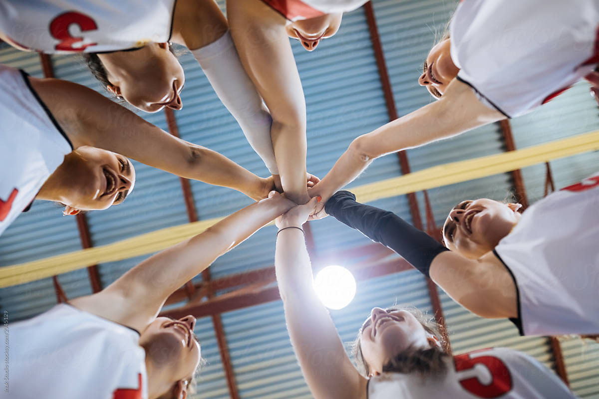 Joyful female volleyball team putting hands together in Madrid, Spain.
