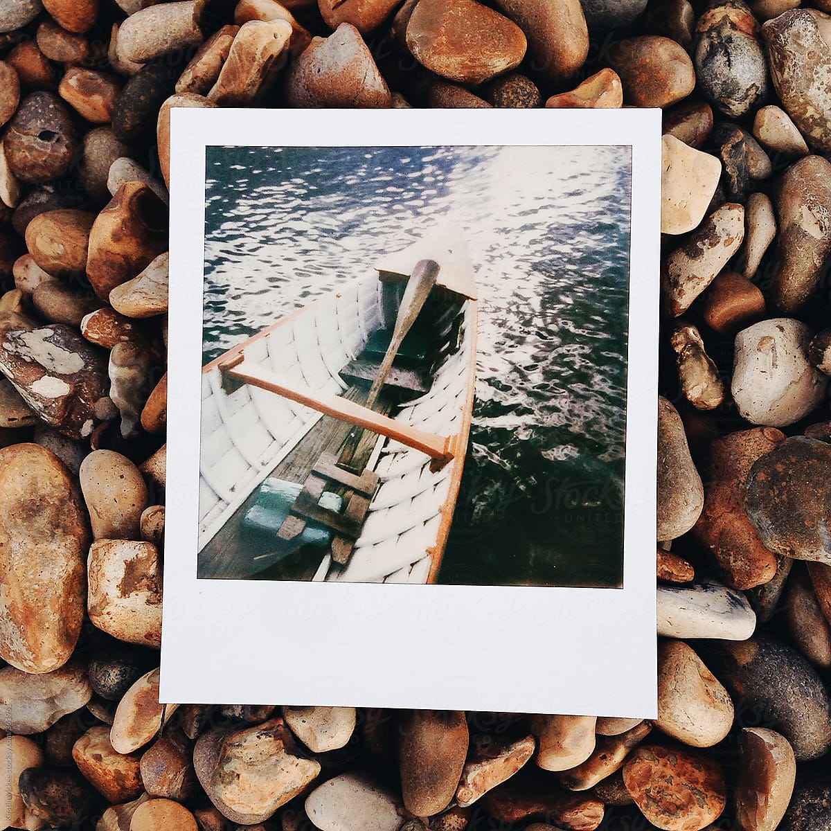 Instant image of a boat in the water, taken on a beach.