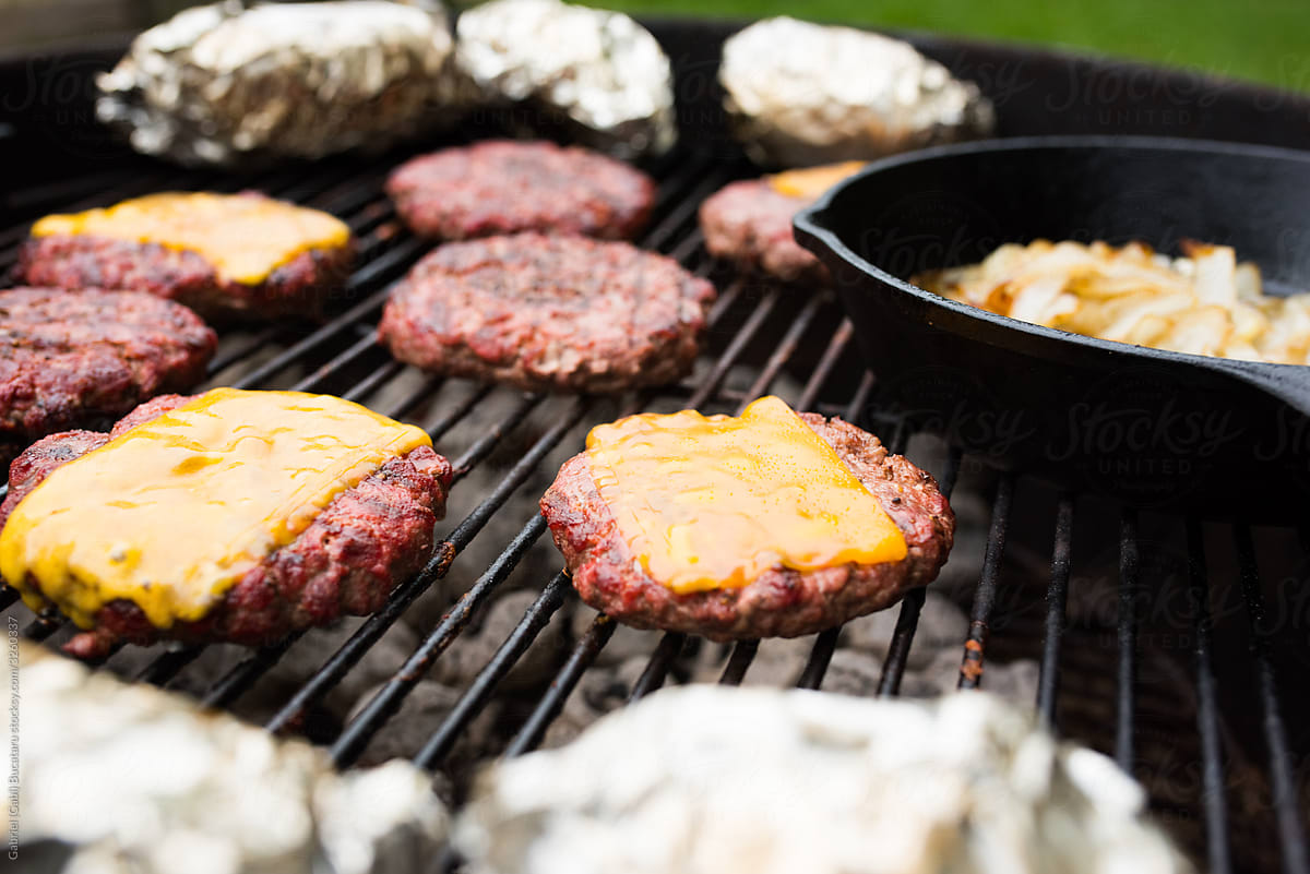 Close up of hamburgers on a charcoal grill from overhead