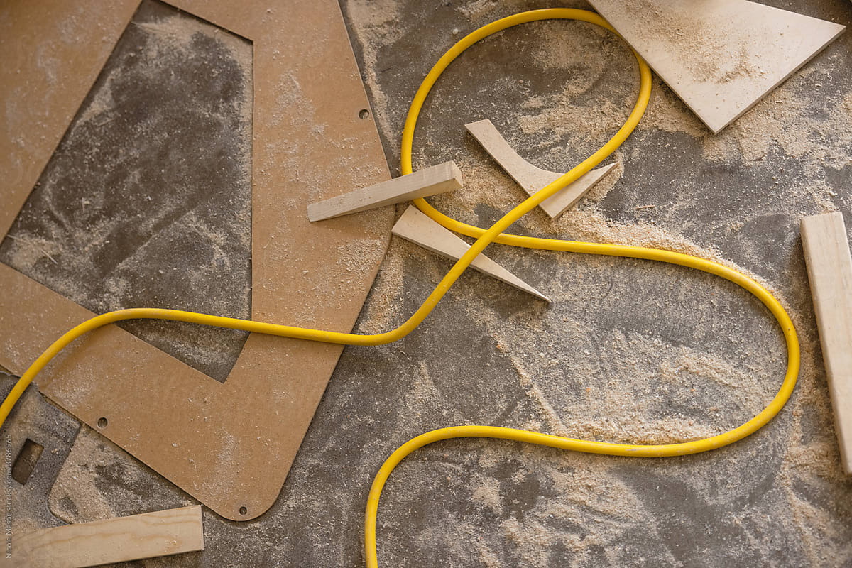 yellow power cord on floor with sawdust and wood