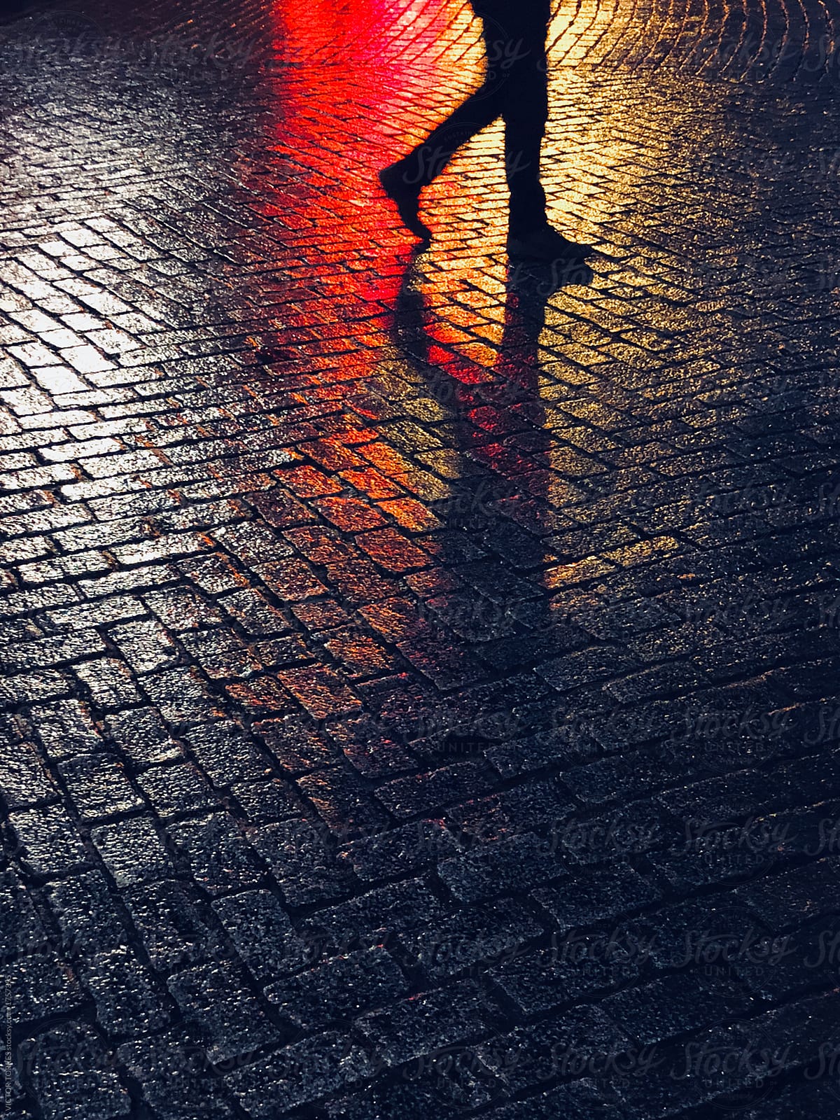 Unrecognizable person walking on asphalt by night