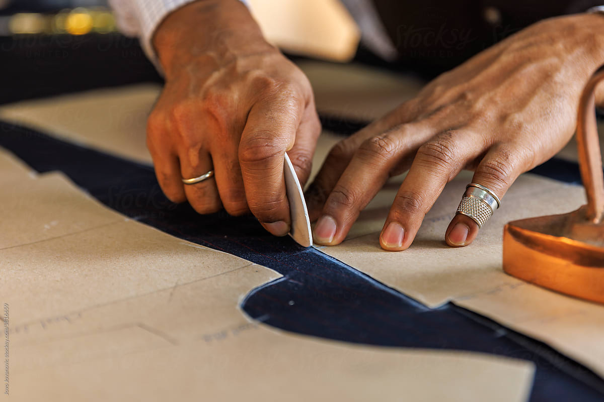 Cropped image of tailor drawing outline of fabric at table