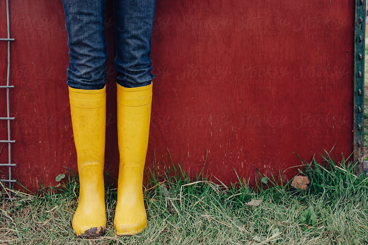 Women\'s legs with yellow muddy rainboots
