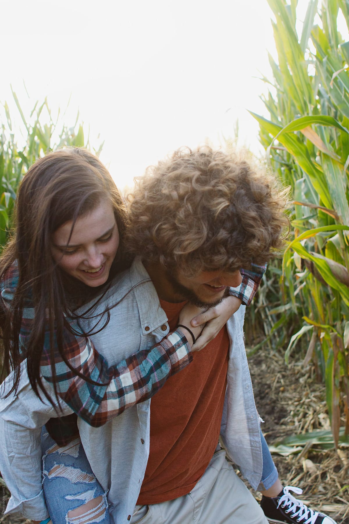 boy gives girl piggy back ride through corn maze