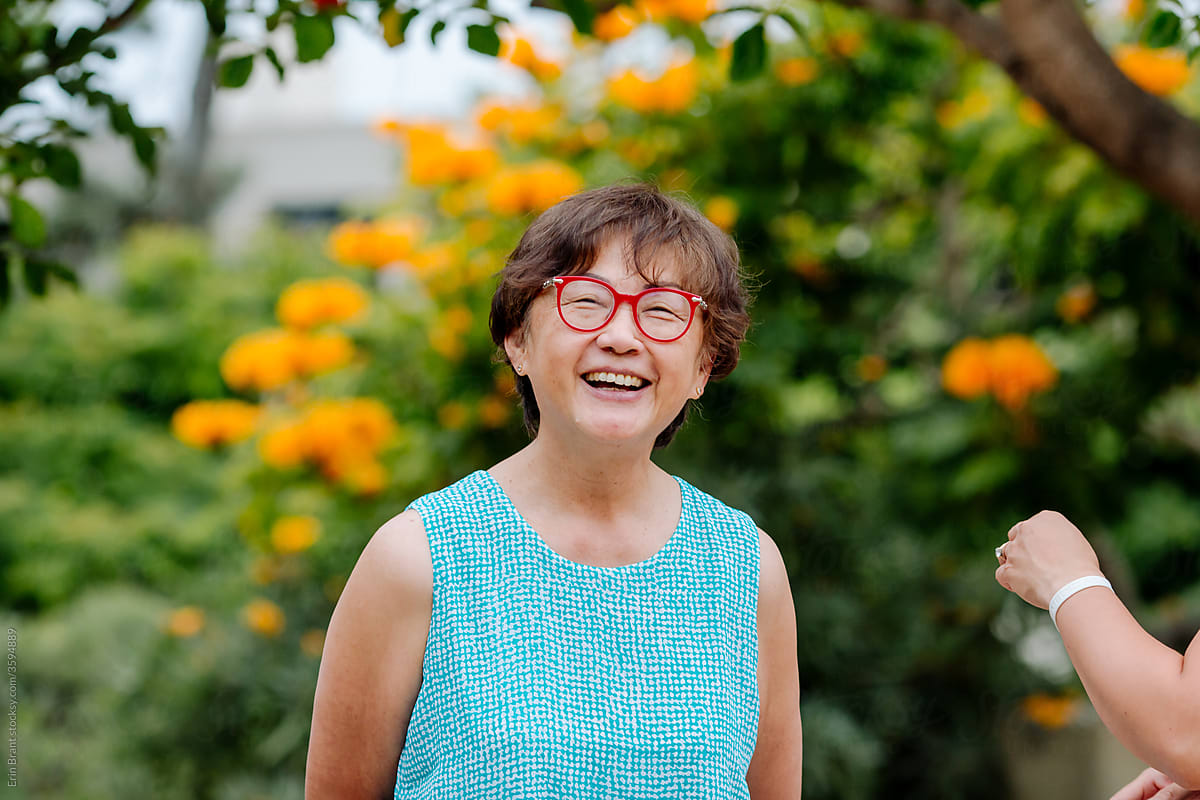 70 yr old smiling asian woman wearing red glasses