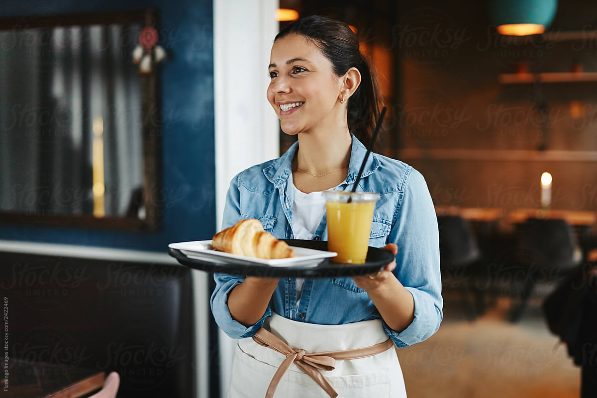 Smiling waitress carrying an order of food in a cafe
