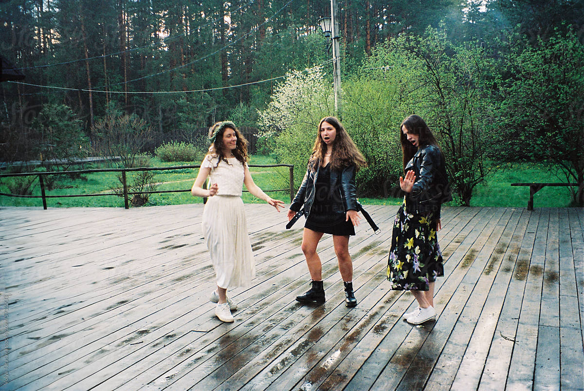 Bride and her girl friends dancing in a forest after rain on wedding