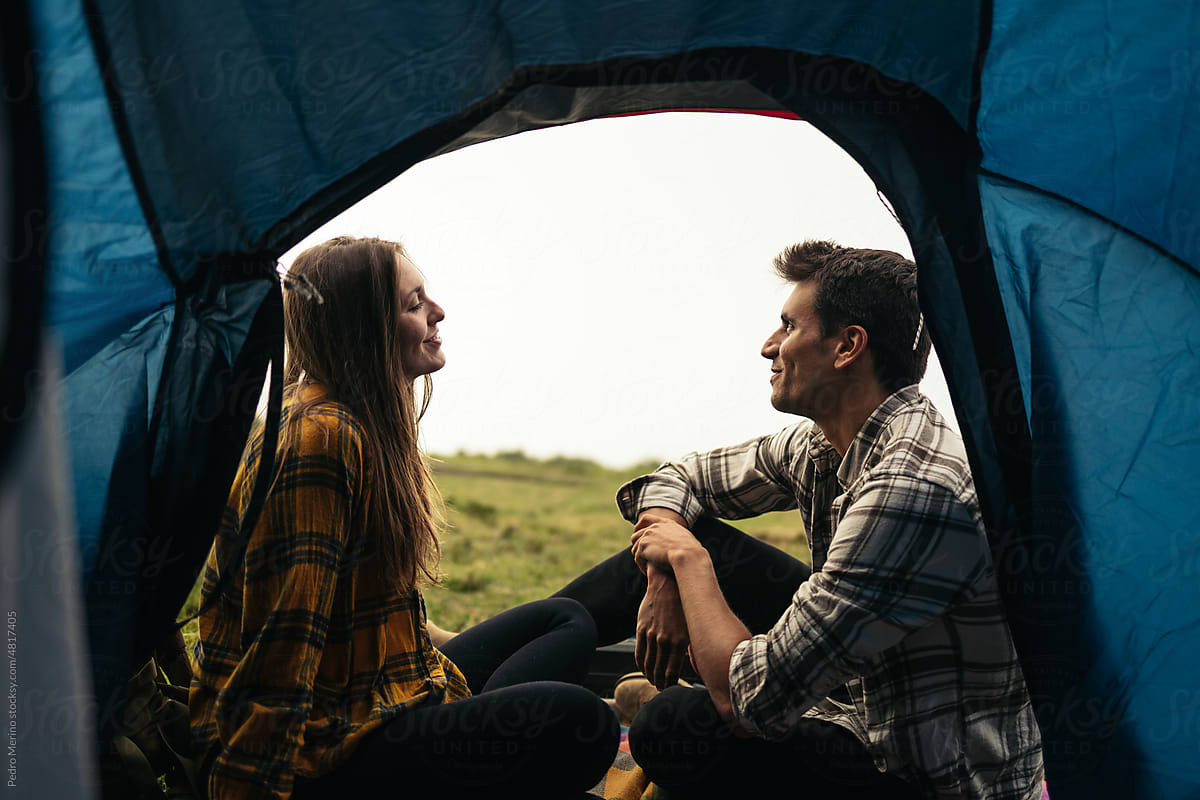 Happy couple talking and relaxing while camping in the woods