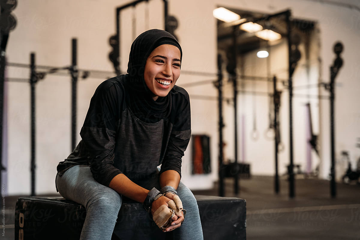 Happy Islamic sportswoman resting after workout in gym