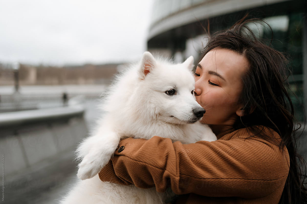 A woman holds her dog in her arms and kisses him
