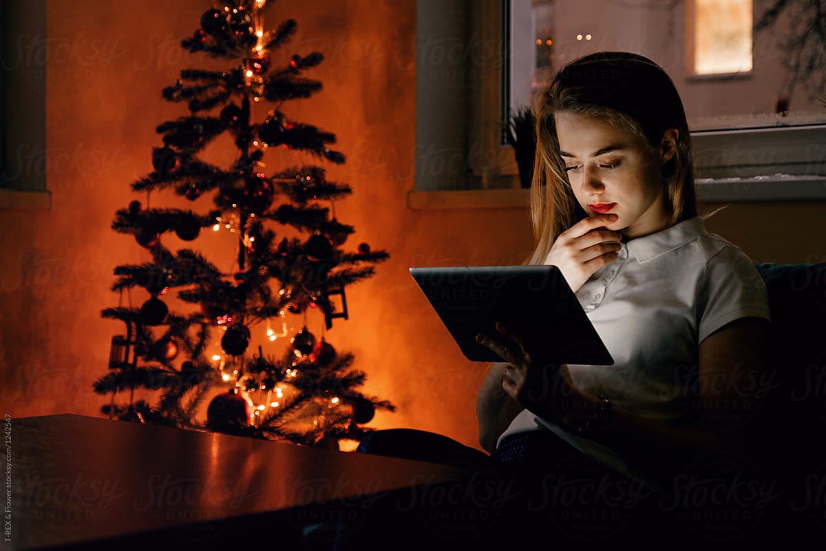 Young female with tablet near Christmas tree