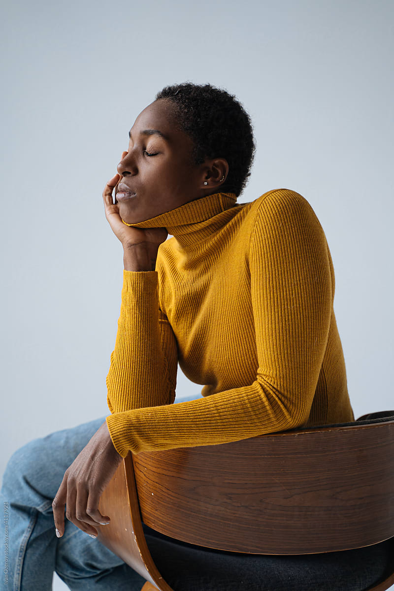 pensive black woman sitting on chair in studio