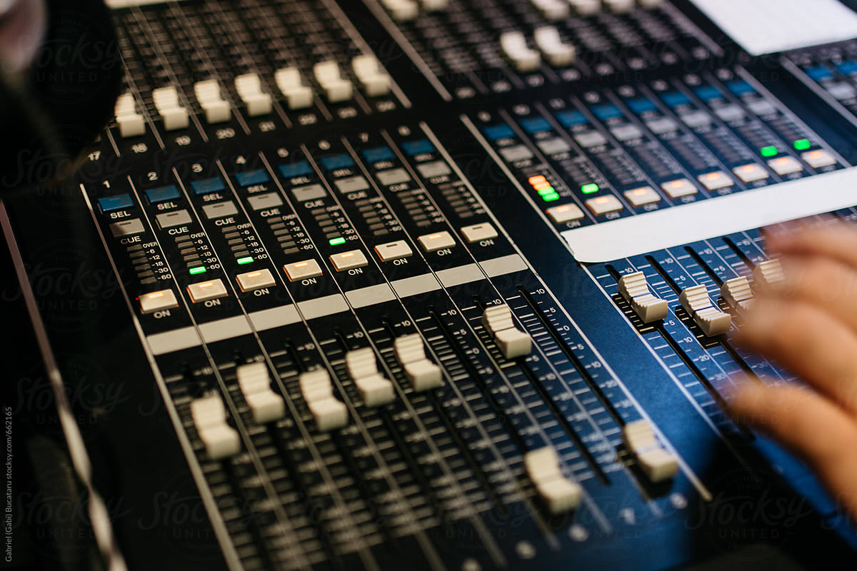 Sound engineer\'s hands on mixer board faders