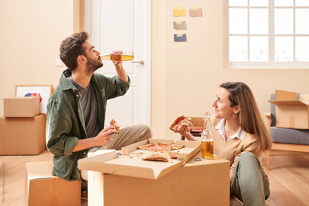 Young couple enjoying pizza and beer during relocation