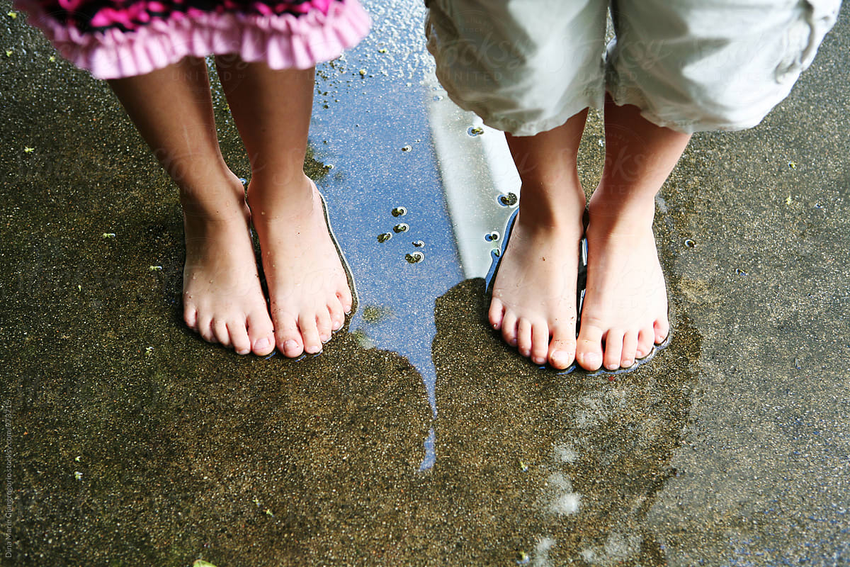 Boy And Girls Legs And Feet Standing On Wet Ground By Dina Marie