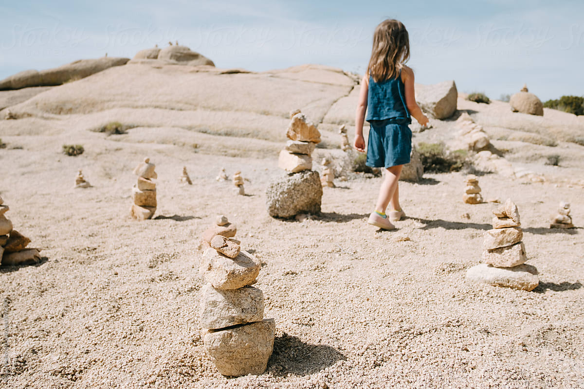 child plays with rocks in desert and makes towers