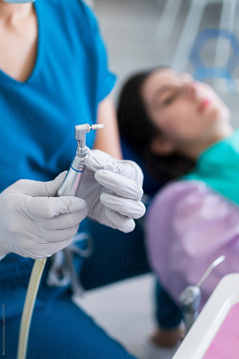 Dentist adjusting a metal instrument next to a patient