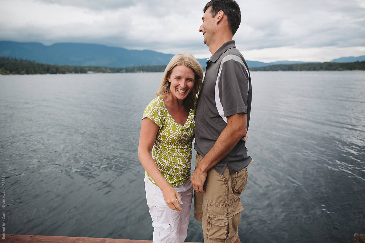 Happy couple in their 40\'s laughing awkwardly on the dock at the lake