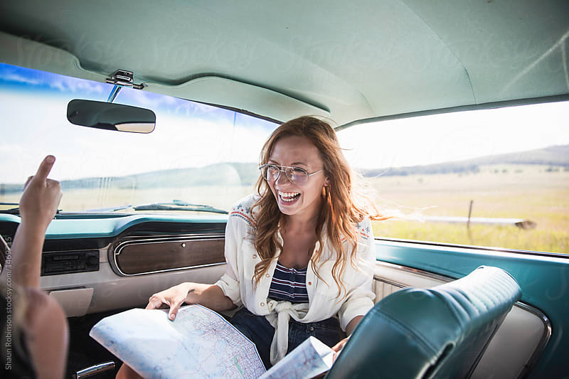 Happy woman in Vintage car giving directions on a map