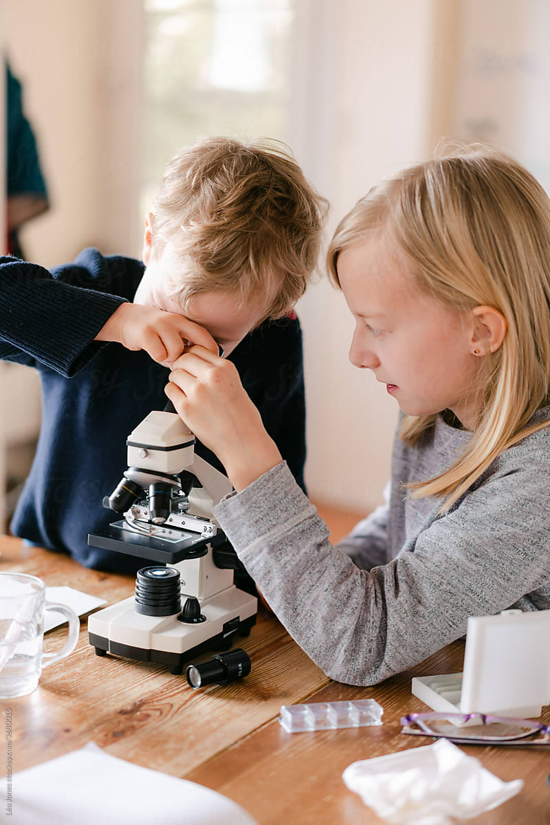 young girl and little brother  looking through microscope