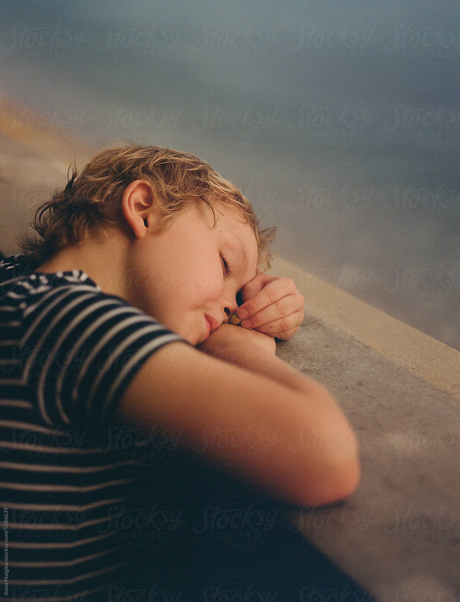 Tired kid on sunset by the beach