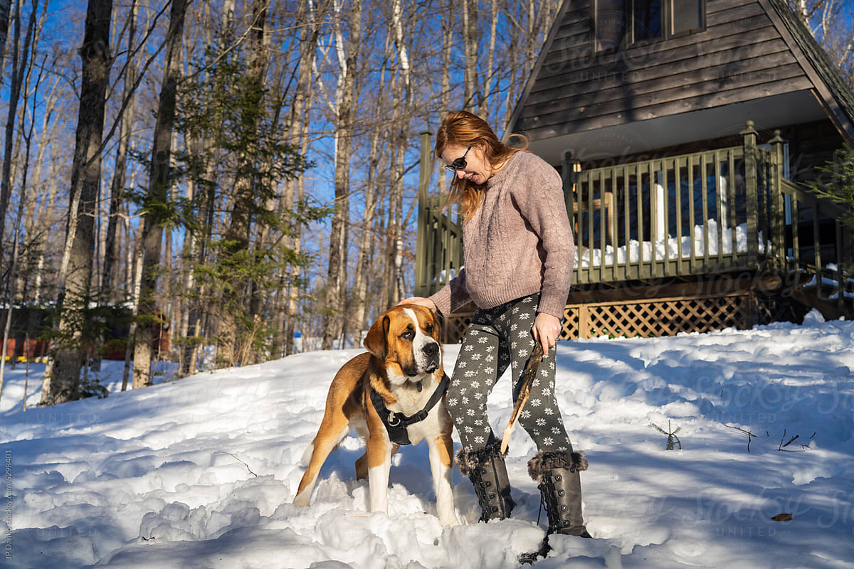 Woman Playing With Dog at Winter Cottage