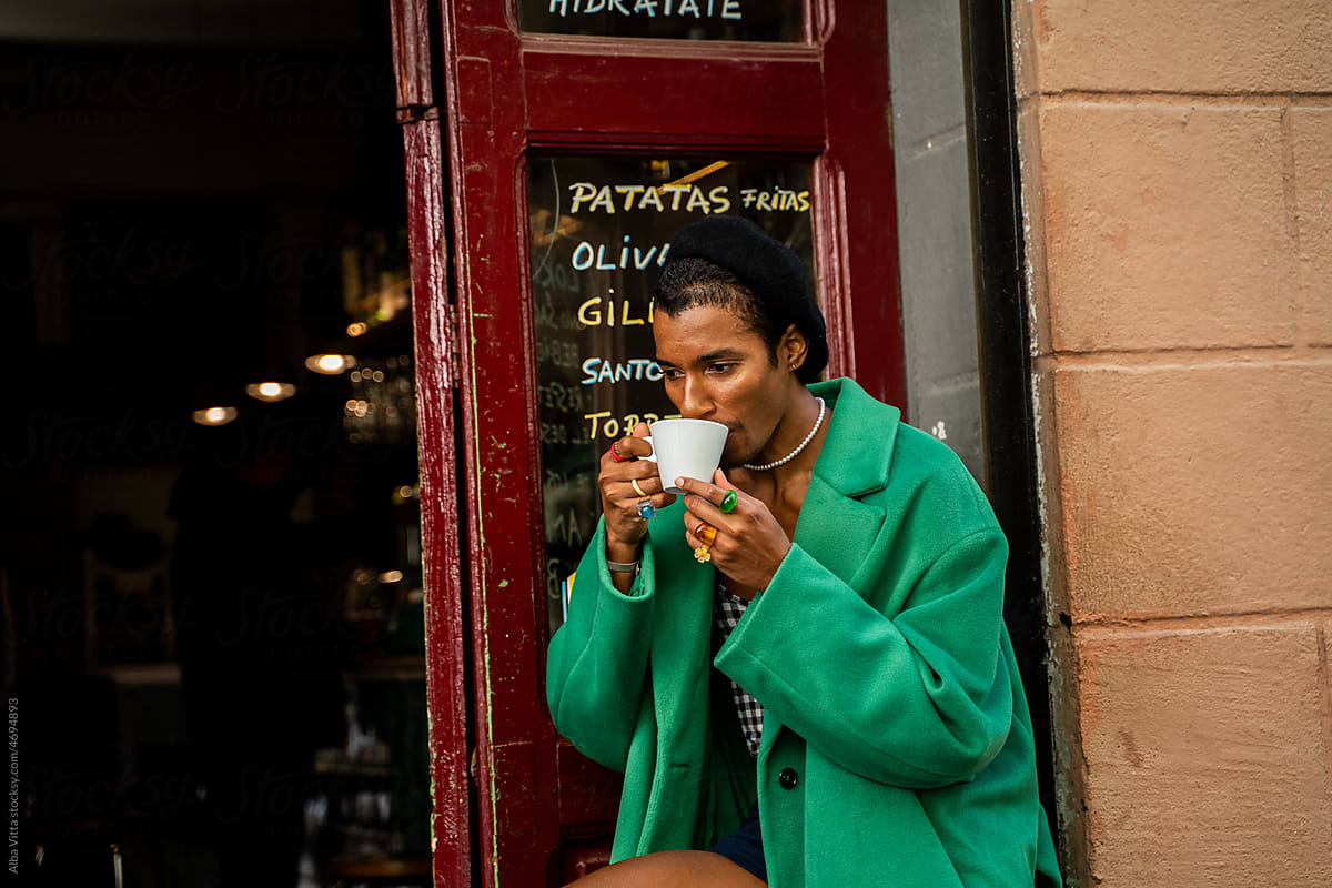 Stylish black man having coffee at street