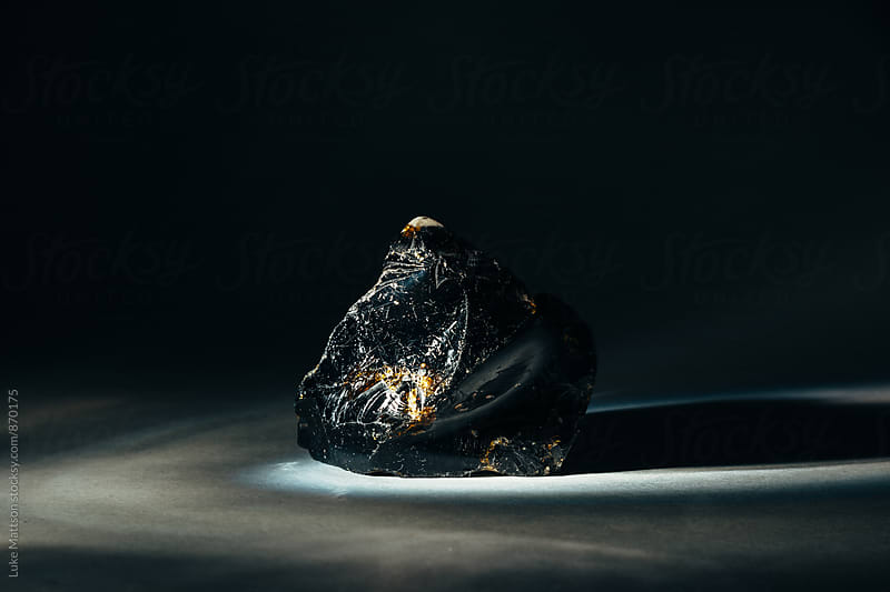 Black Obsidian Stone With Edges Illuminated By Faint Light