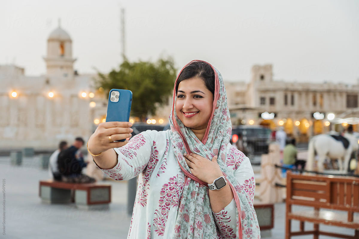 Smiling Indian woman taking selfie in city