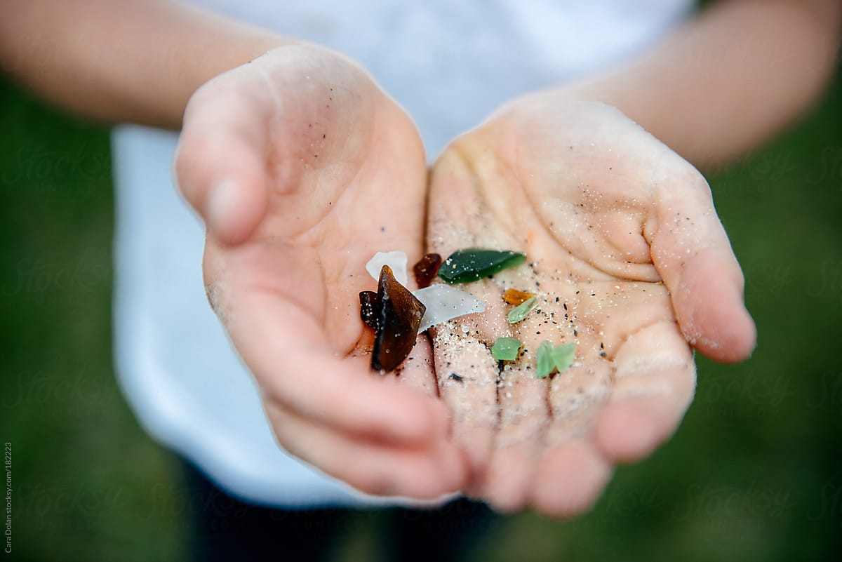 Child holds a small collection of colored sea glass in cupped hands
