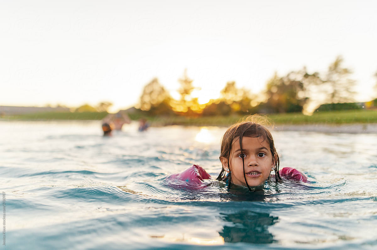 Girl swimming in pond at sunset.