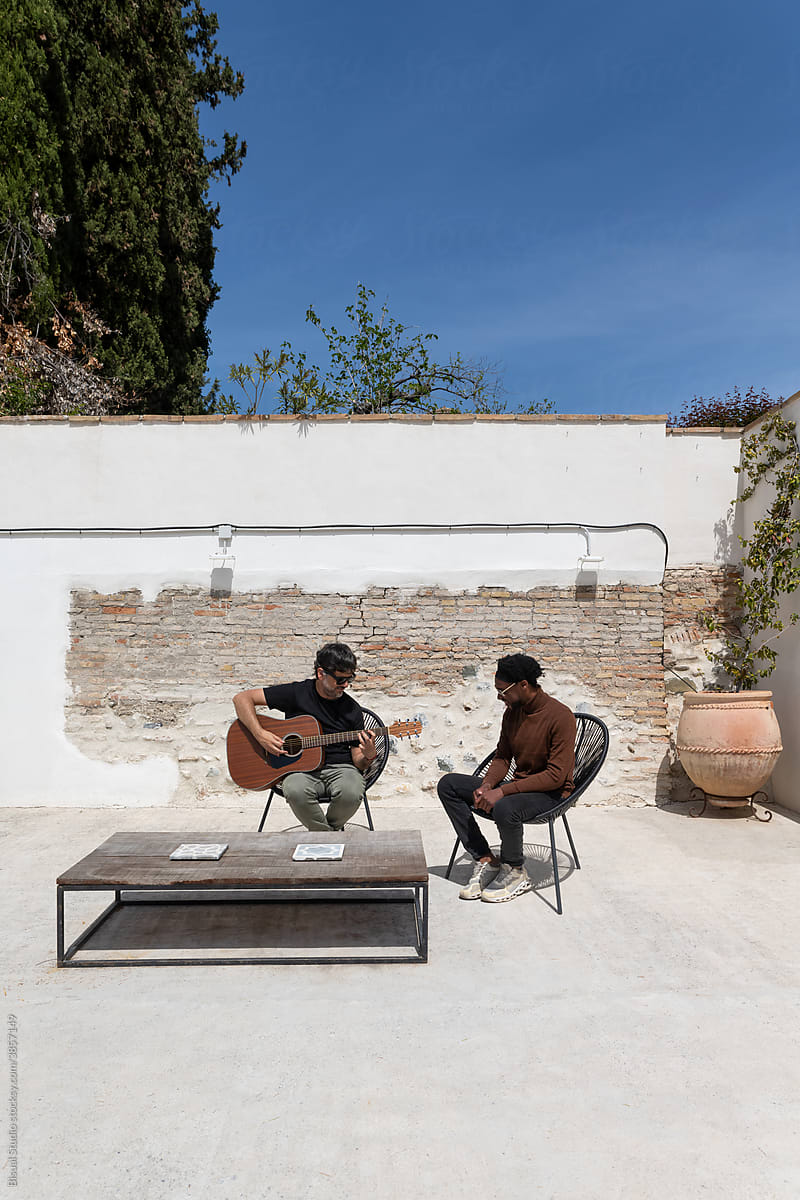 Diverse men creating music on terrace