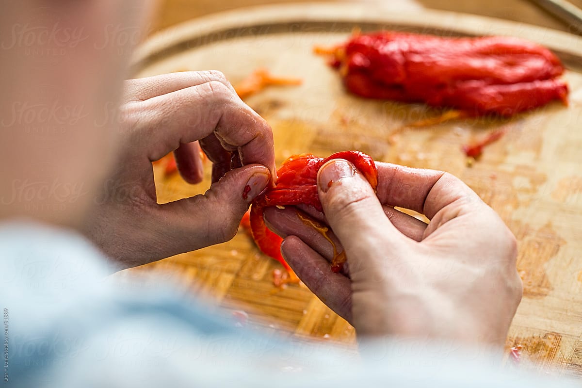 Man’s hands peeling roasted peppers