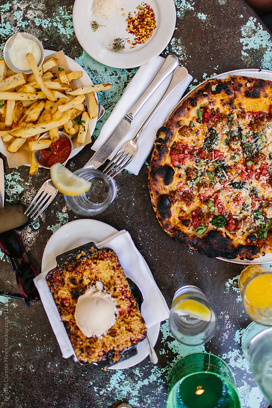 From above shot of pizza, fries and pie. Brunch food on a rustic table.