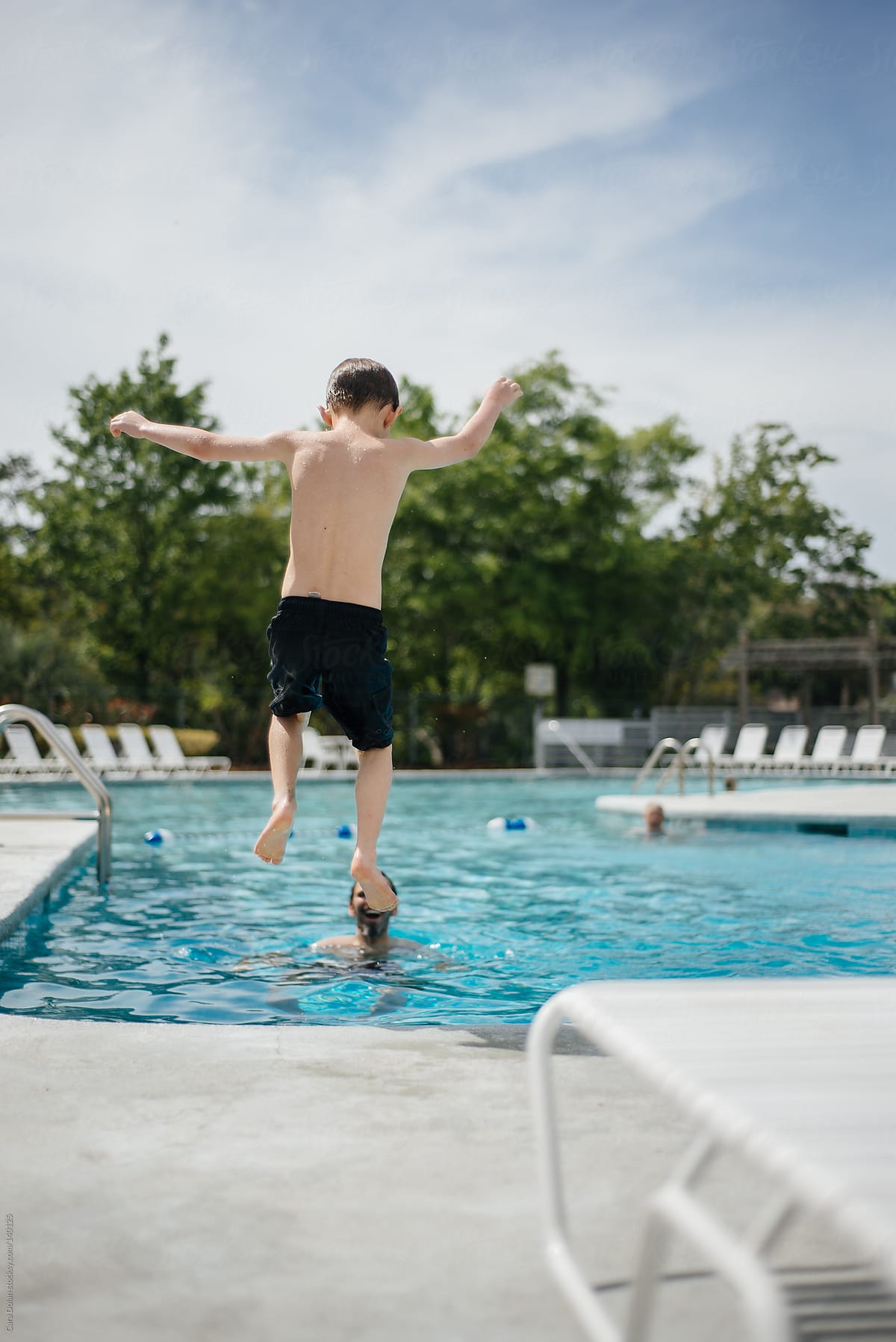 Boy leaps into a swimming pool while on vacation with his family