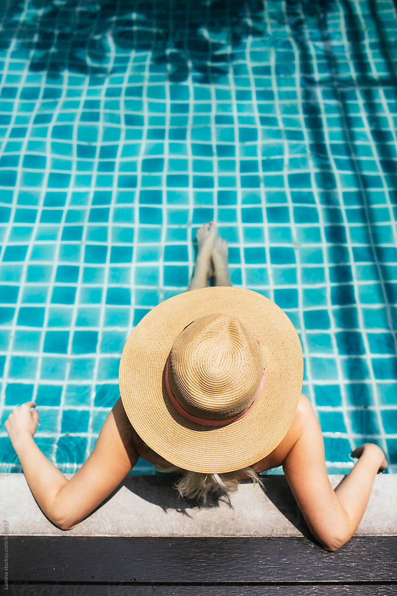 Woman With A Hat Relaxing In A Swimming Pool by Stocksy
