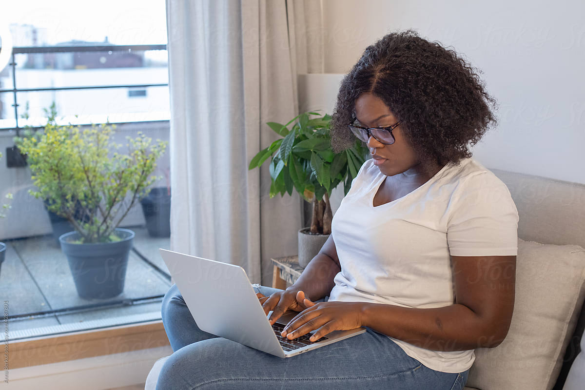 black woman working on laptop computer at home, writing email