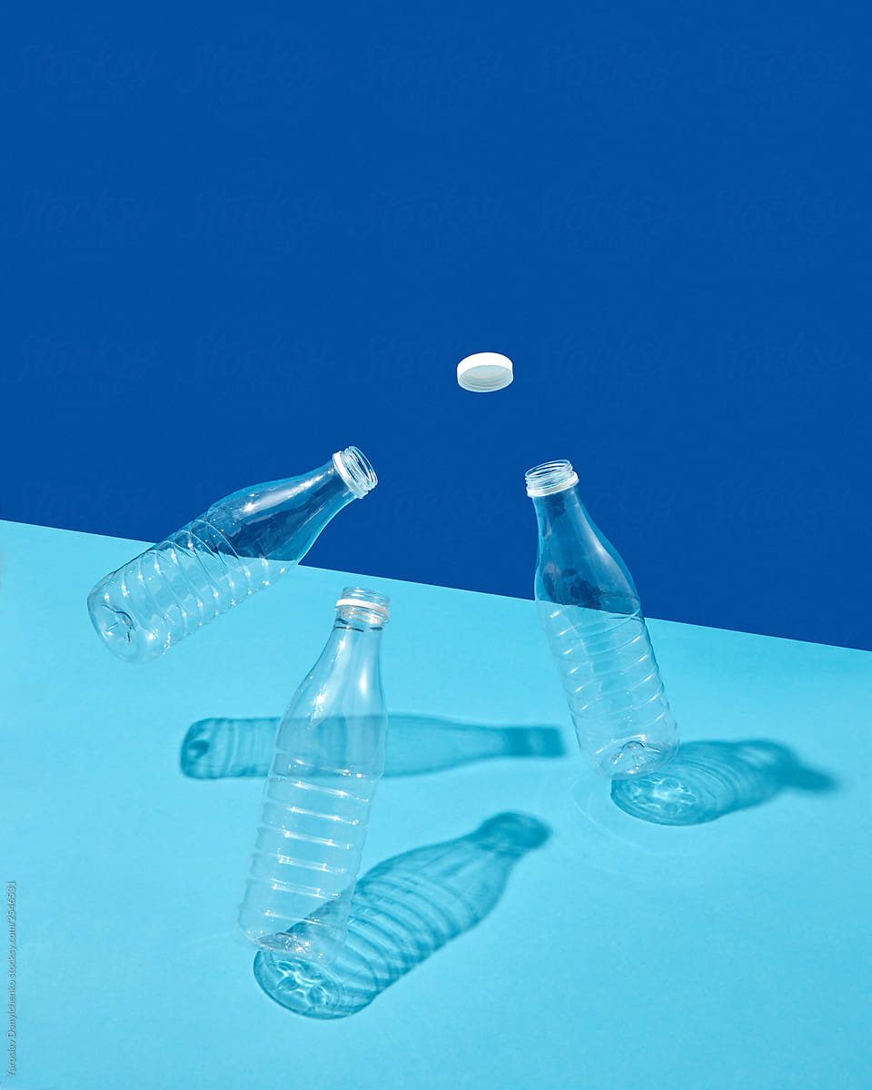 Plastic cap and bottles in the air on a double blue background