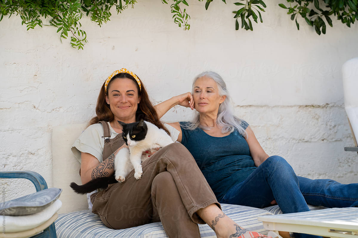 Mother and adult daughter with cat relaxing at home