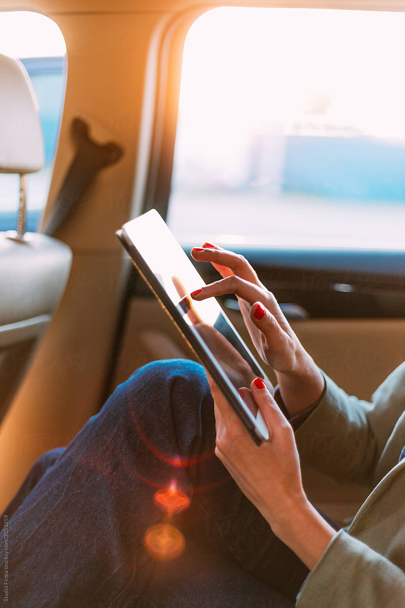 A Woman in a Car Using a Digital Tablet